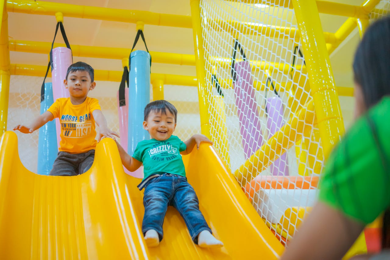 About Two boys enjoying playful moments on a colorful indoor playground slide.